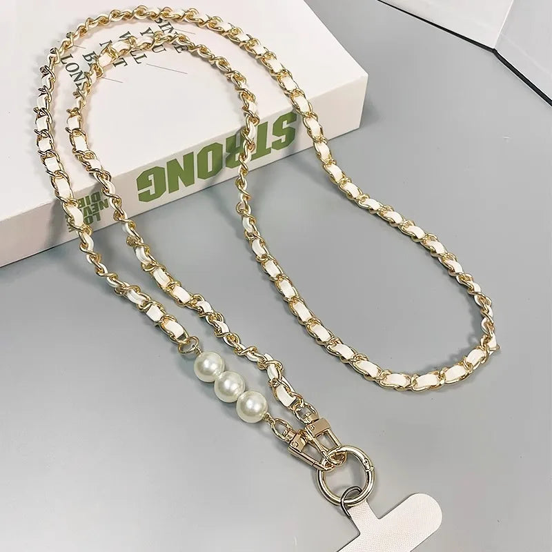 White leather and metal chain phone strap, with pearl detailing and universal phone tether on a gray surface