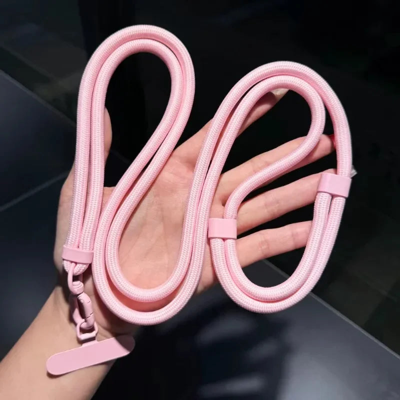 Pink braided lanyard with adjustable strap held in a hand against a blurred background