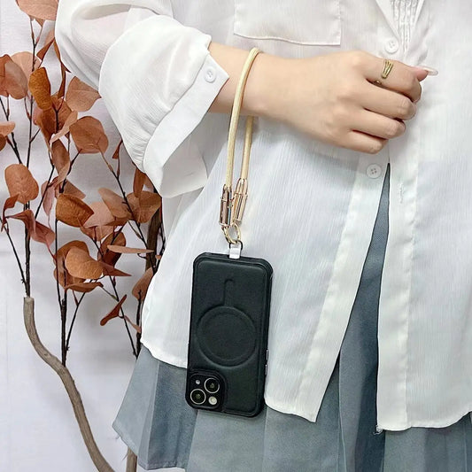 Person holding a black phone with a yellow phone strap against a neutral background