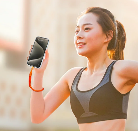 Women running with cell phone in her hand. The women is wearing a strap around her wrist that connects to the cell phone so that she does not drop it while running
