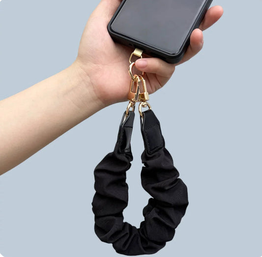 black fabric phone wrist strap that looks like a scrunchy