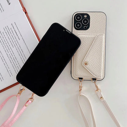 Black phone next to a white leather phone case with strap on a light surface