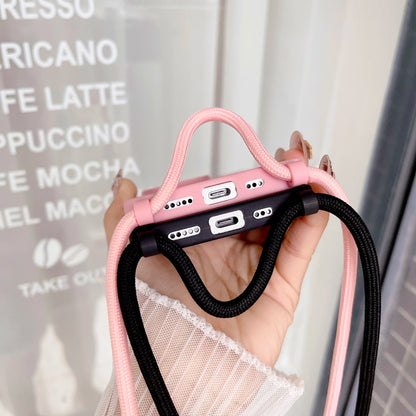 Pink and black phone cases with straps held up by a hand to show the charging port, blurred background