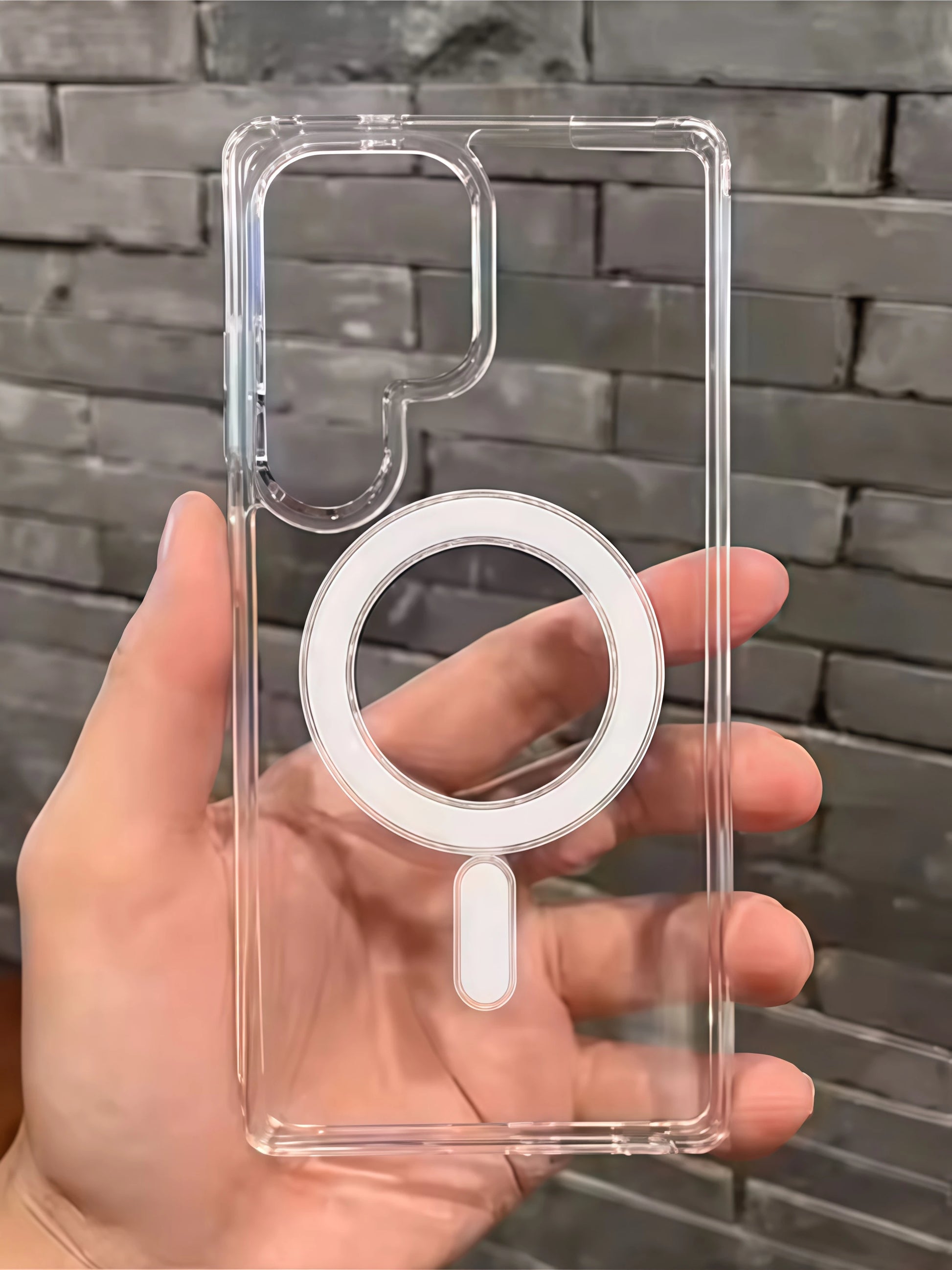 Clear phone case with ring holder held by a hand against a stone wall background