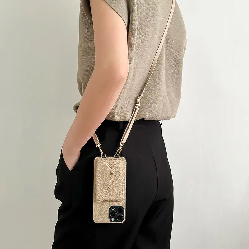 Person wearing a khaki leather phone case with a strap against a plain background