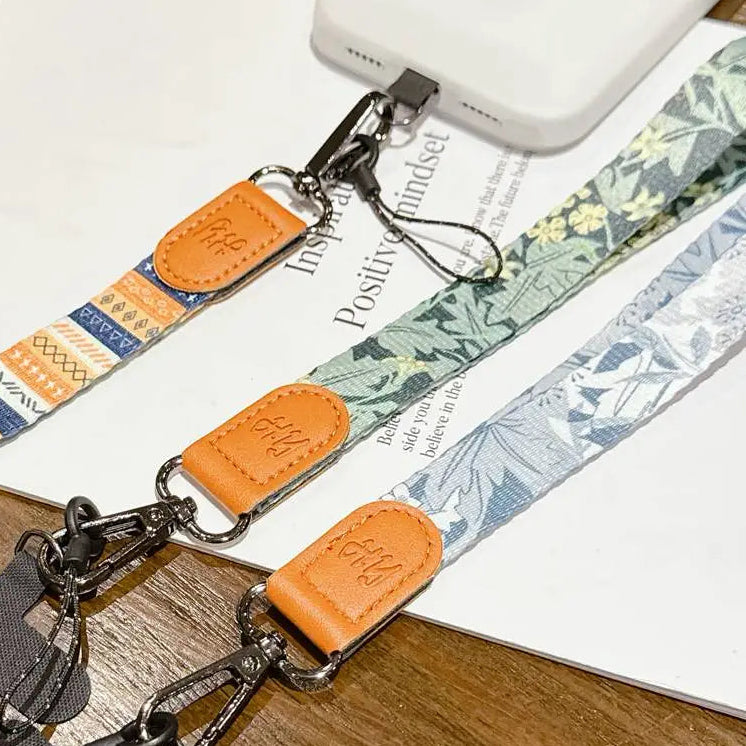 Multicolored phone straps with leather ends on a wooden surface