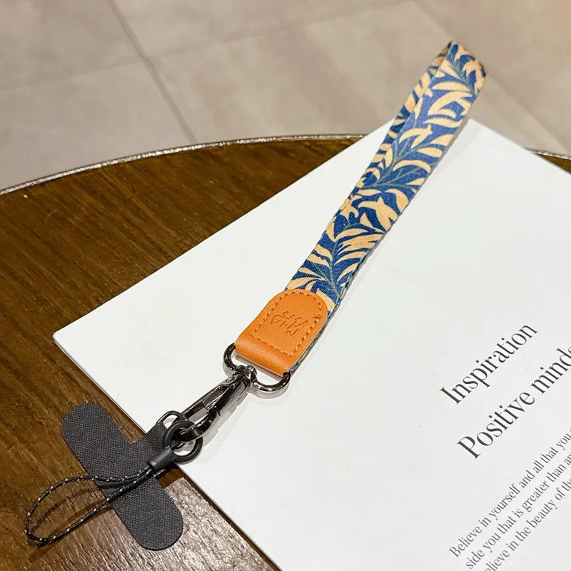 Lanyard with blue leaf pattern and orange accent on a book