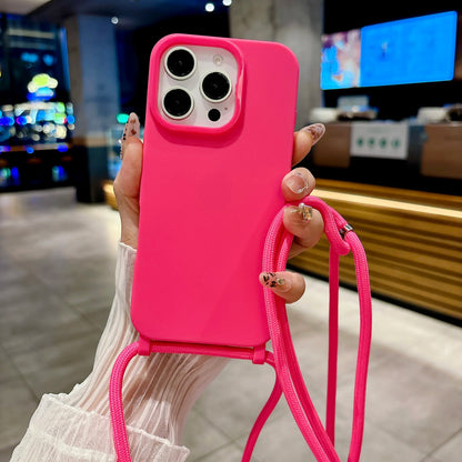 Rose pink phone case with a strap held by a person in an indoor setting