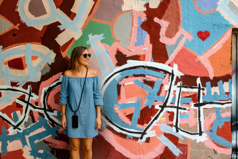 Woman in a blue dress standing in front of a colorful abstract mural.