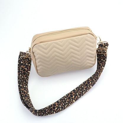 Beige quilted handbag with a leopard print strap on a white background